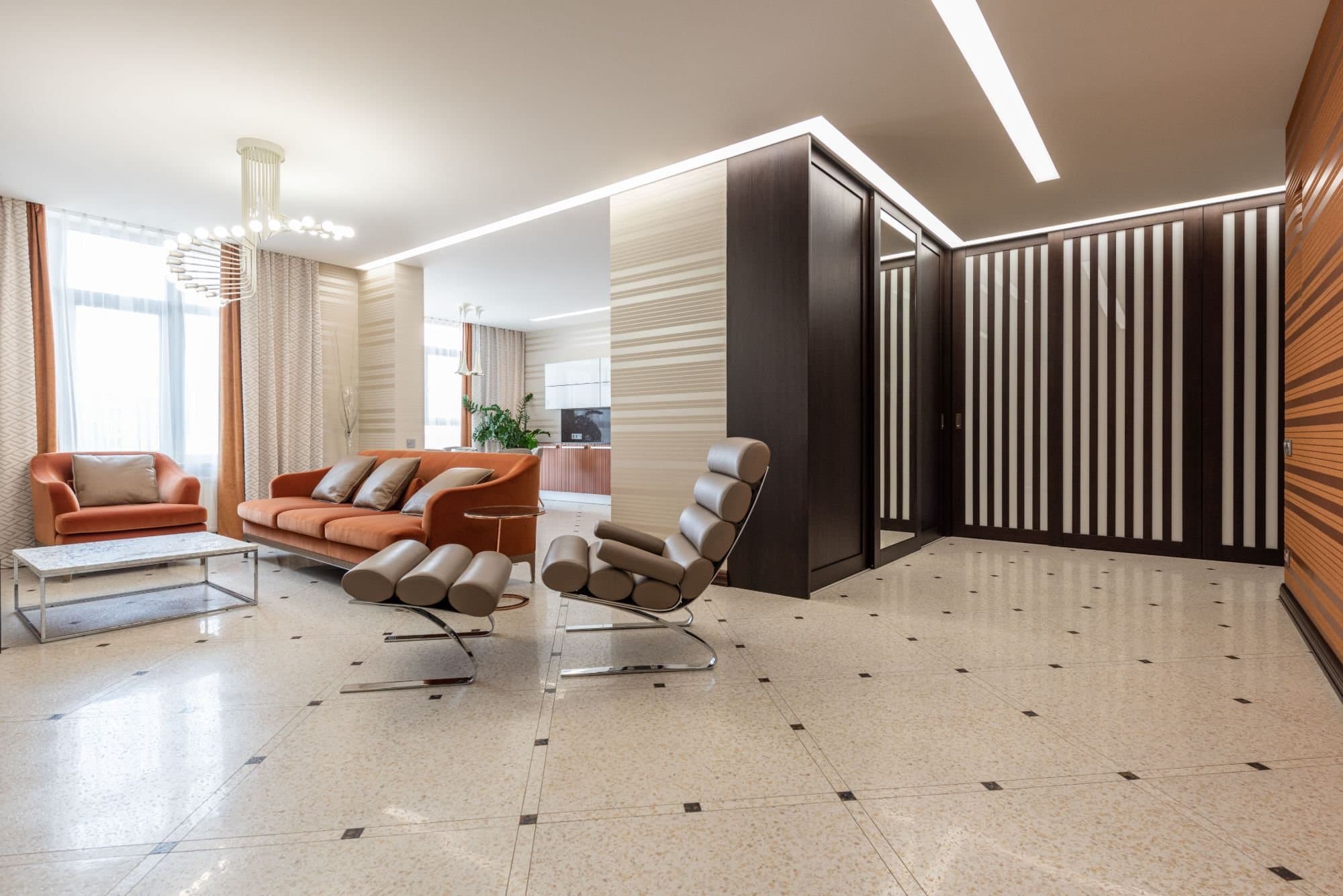 Open showroom floor with terrazzo paving, dark timber joinery and two chrome-framed leather chairs
