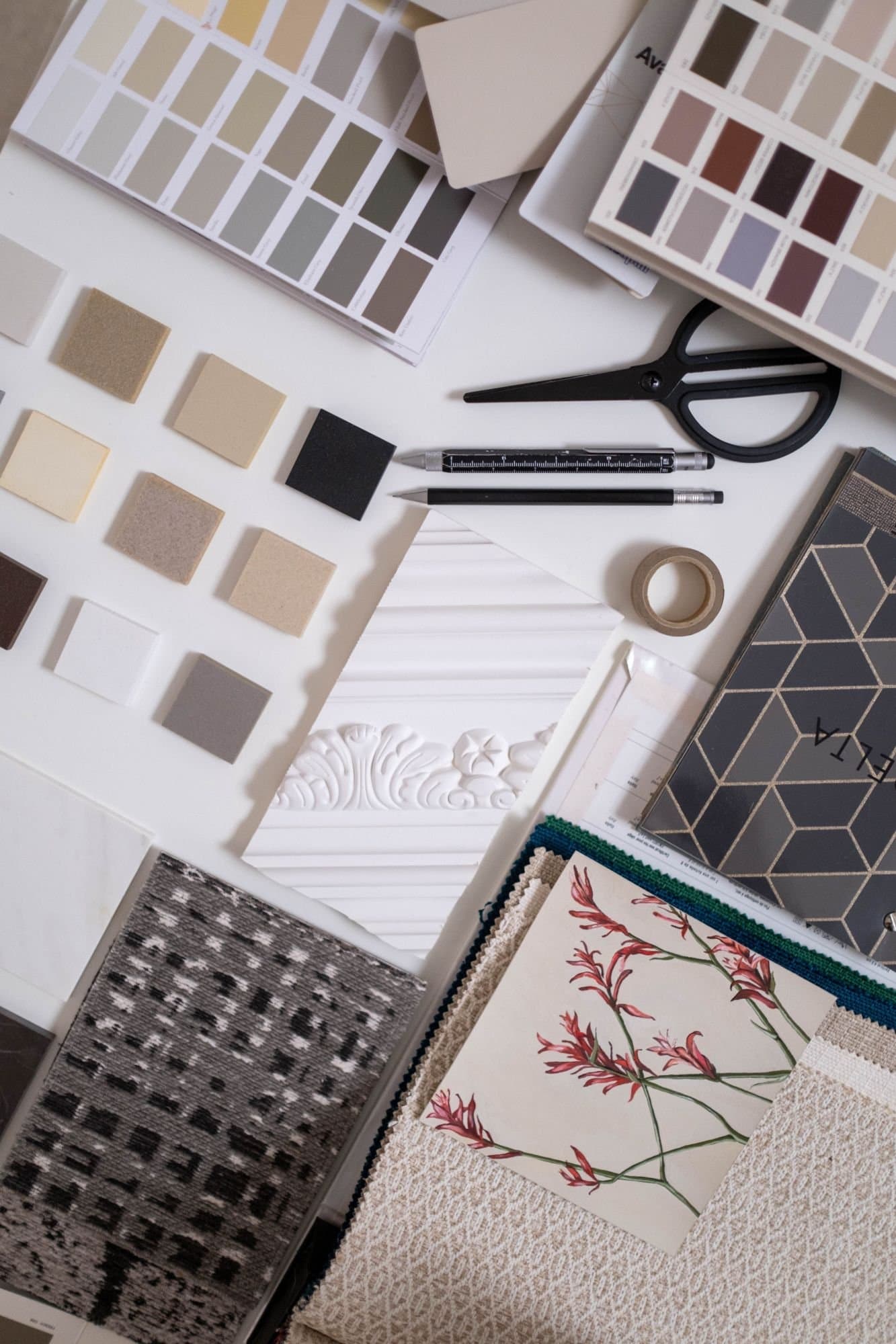 Flat lay of paint charts, stone and textile samples on a white table